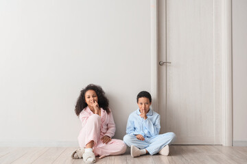 Poster - Little African-American children in pajamas showing silence gesture near door at home