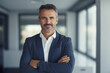 © Enrique - Happy middle aged business man ceo standing in office arms crossed. Smiling mature confident professional executive manager. businessman concept