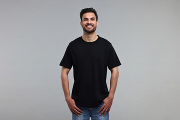 Wall Mural - Smiling man in black t-shirt on grey background