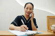 © DragonImages - Spa salon receptionist checking price list and filling form on tablet computer