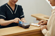 © DragonImages - Manager helping client to swipe credit card when paying for procedure