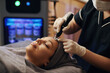 © DragonImages - Woman getting micro needling treatment in beauty salon