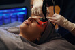 © DragonImages - Woman getting red light therapy and face massage in beauty salon