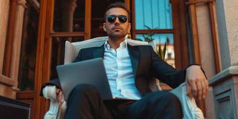 Professionalism, seniority, and modern lifestyle freelancer at any age concept. Adult man in a business suit working on a laptop outdoors on luxury hotel on background