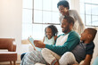 © peopleimages.com - Reading, smile and black family with book on sofa for bonding together on fathers day at home. Happy, knowledge and African parents relaxing with children in living room with fantasy story or novel.