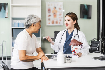 Wall Mural - A young Asian female nurse providing healthcare services at her desk, caring for an elderly woman patient. They discuss health checklists and medical advice in a professional setting.