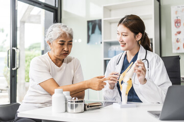 Wall Mural - A young Asian female nurse providing healthcare services at her desk, caring for an elderly woman patient. They discuss health checklists and medical advice in a professional setting.