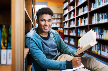 Poster - Student, man and portrait with learning in library for studying, scholarship or writing in book for exam information. Education, person or happy with notebook for research notes or knowledge on floor
