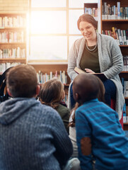 Library, children and teacher reading book, education and learning with knowledge, storytelling and kindergarten. Educator, woman and kids on floor, fun and fantasy stories with development or relax