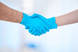 © peopleimages.com - Healthcare, trust or doctors with handshake at hospital for medical, partnership or surgery collaboration. Gloves, welcome or surgeon people shaking hands at clinic for teamwork, agreement or support