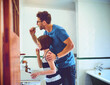 © peopleimages.com - Oral health, teaching and father brushing teeth with kid for wellness, hygiene and morning routine. Bathroom, dental care and dad with girl child for mouth cleaning treatment with toothbrush at home.