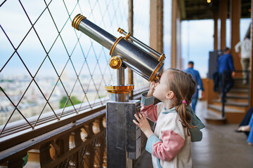 Wall Mural - Adorable preschooler girl enjoying the view from the Eiffel tower to the Field of Mars in Paris, France.