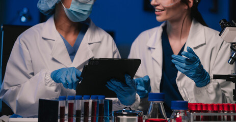Wall Mural - team of biochemical research scientists working with a microscope for vaccine development in pharmac