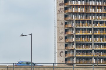 Wall Mural - A modern construction site with a high-rise building under construction and a car passing by