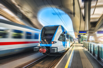 Wall Mural - high-speed blue passenger train moving at railway station platform at sunset. train station. modern 