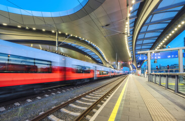 Wall Mural - high-speed passenger train in motion at the illuminated railway station at night. moving red modern 