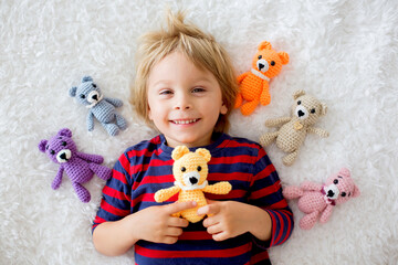 Sticker - Little toddler child, cute blond boy, lying down in bed with many teddy bears, handmade amigurumi toys at home