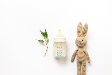 Wall Mural - Feeding time for baby. Milk in bottle and toy on white background, top view