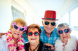 © Arnell K/peopleimages.com - Group, smile and sunglasses with elderly friends in hallway of retirement home for goofy party on weekend. Portrait, funny and eyewear with happy mature people hugging in senior care apartment