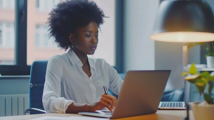 Aufkleber - Young African American business woman sitting at working desk in office using laptop computer browsing online banking website updating personal details and taking notes in notebook : Generative AI
