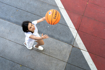 Shooting basketball. Happy Asian woman having fun practice to shoot the ball into the hoop. Female basketball player enjoy training exercise, leisure activity, action sport. copy space.