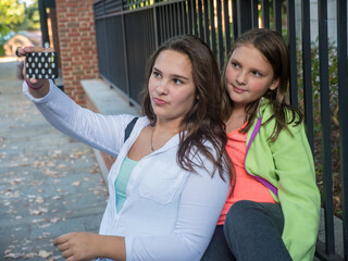 Two girls city park taking a selfie on smart phone