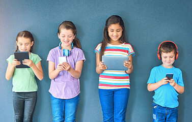 Poster - Studio, technology and group of children for elearning, education and online research with smile. Happy students, girls and boy with digital app of tablet, smartphone and headphone by blue background