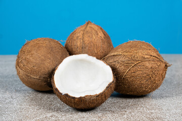 Wall Mural - Whole coconuts and half a coconut on a blue and gray background close-up