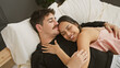 © Krakenimages.com - A loving couple embracing on a bed, showcasing affection and comfort in a cozy bedroom setting.