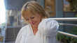 © Krakenimages.com - Middle-aged woman in city street rubbing her neck painfully under bright urban outdoor setting.