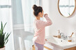 © LIGHTFIELD STUDIOS - A brunette woman in a modern bathroom is brushing her teeth as part of her beauty and hygiene routine.