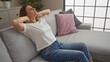 © Krakenimages.com - A relaxed young blonde woman enjoys her time at home, sitting comfortably on a sofa in a modern living room.