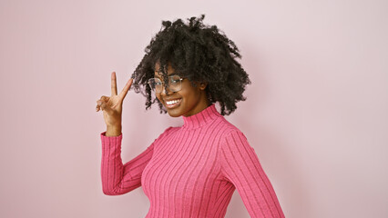 Wall Mural - African american woman posing playfully in a pink sweater against a light background