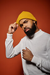 Wall Mural - Handsome African American man with a beard wearing a yellow hat in a stylish pose against a colorful backdrop.