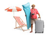 © Ljupco Smokovski - Male tourist with inflatable mattress and a suitcase next to a beach chair and umbrella