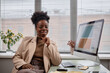 © Seventyfour - Medium shot portrait of attractive adult African American lawyer or manager executive posing and smiling at camera while sitting at working desk with computer, copy space