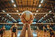 © LightoLife - Close-up of hands holding volleyball in gymnasium with players in background, capturing the intensity and focus moments before the match begins.