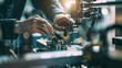© VK Studio - Hands maneuver intricate mechanical parts on an industrial machine, with a focus on the precision and skill required in a bustling workshop.