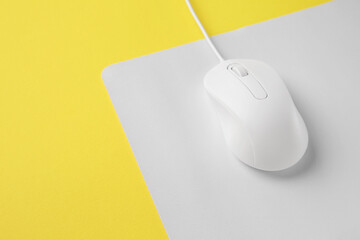 One wired mouse with mousepad on yellow background, closeup