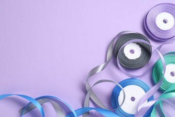 Wall Mural - Ribbon reels in different colors on violet background, flat lay. Space for text