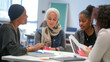 © tiagozr - Diverse group of female students studying together in a classroom.