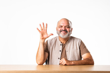 Wall Mural - Indian asian retired old man counting numbers using fingers and showing it to camera with smile