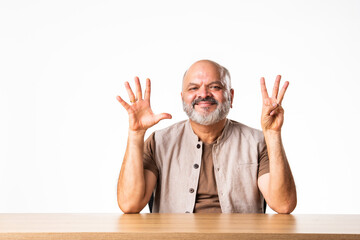 Wall Mural - Indian asian retired old man counting numbers using fingers and showing it to camera with smile