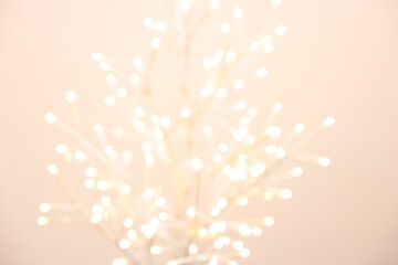 Wall Mural - Decorative tree with lights on beige background, blurred view