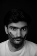 © Sanket Mishra - Young Indian man having a black hand print painted on face looking at camera. gender fluid lgbt identity racial equality concept. Racism concept portrait. Face painting on male face.
