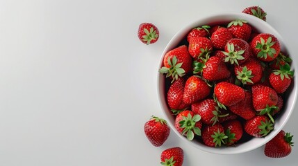 A bowl of red strawberries sits on a white table