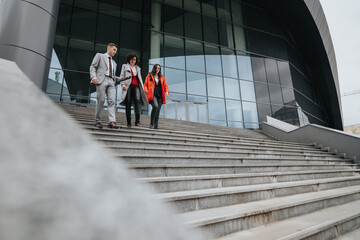 Dynamic image of business partners descending stairs outside a modern office building, showcasing teamwork and professionalism.