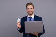 © be free - Businessman business man in suit showing credit or debit card to pay online on laptop isolated on grey
