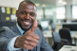 © Emanuel - Confident businessman in an office setting giving a thumbs up gesture, signaling approval, success, or a positive outlook