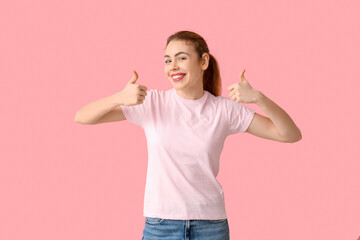 Wall Mural - Beautiful young woman with hearing aid showing thumb-up gesture on pink background